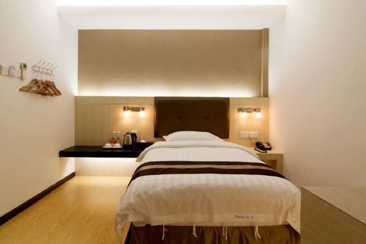 Habitación de hotel con cama, mesitas de noche y estante en la pared.