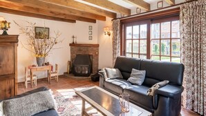 A cozy living room with a fireplace, wooden beams, a sofa, and a coffee table. - Farmhouse in Beveren near Beach & Garden (Beveren a/D Ijzer)