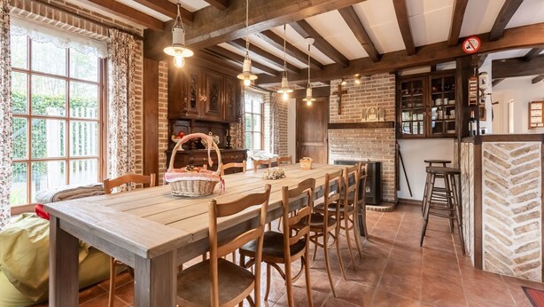 A rustic dining area with a wooden table and chairs, a brick wall, and hanging light fixtures. - Farmhouse in Beveren near Beach & Garden (Beveren a/D Ijzer)