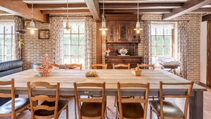 A spacious dining area with a large wooden table, six wooden chairs, and hanging pendant lights. - Farmhouse in Beveren near Beach & Garden (Beveren a/D Ijzer)