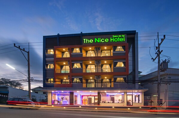 Un hotel con fachada moderna, varios balcones y una entrada bien iluminada.