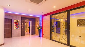 Un moderno vestíbulo de hotel con piso pulido, un mostrador de recepción y un muro divisorio de vidrio.