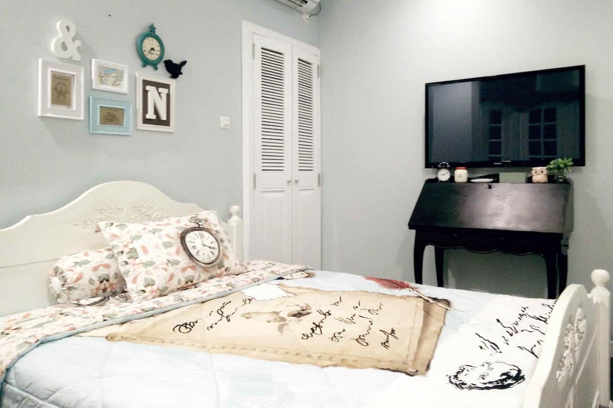 Une chambre à coucher comprenant un lit, une télévision, une commode et un placard.