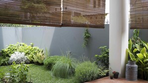 A garden area with various plants and a metal barrel. - Cottonwood Bed & Breakfast House (Bandung)