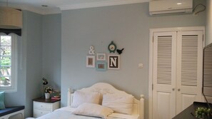 A bedroom with a bed, bedside table, wall decorations, and a window. - Cottonwood Bed & Breakfast House (Bandung)