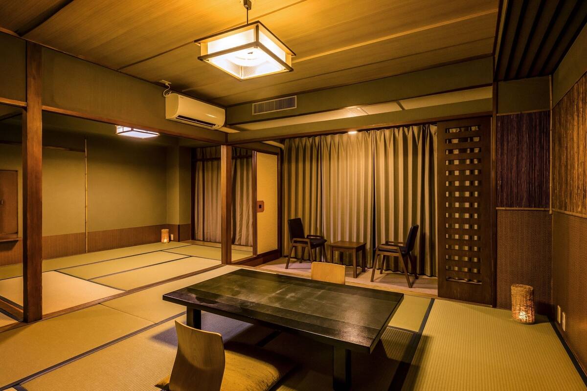 A traditional Japanese room with tatami flooring, a low table, and sliding doors.