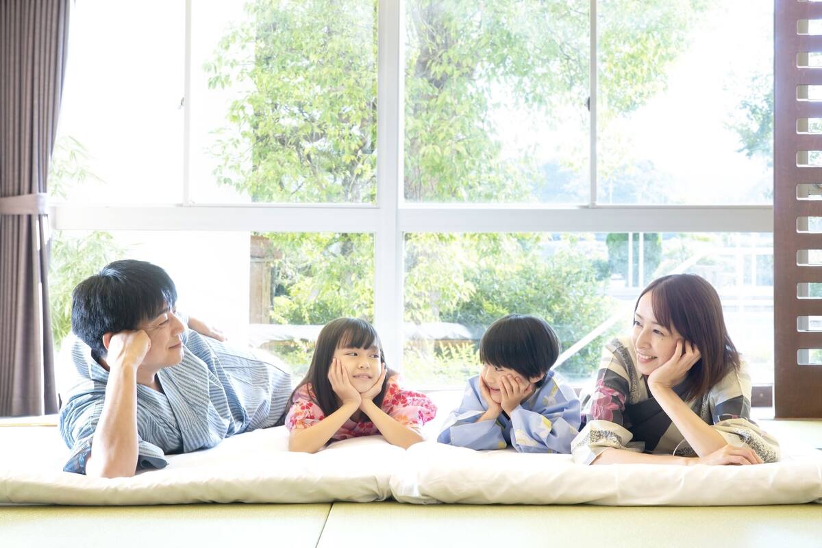 A room with a tatami mat floor, large windows with a view of trees, and a shoji screen.