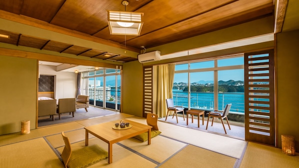 Una habitación tradicional japonesa con suelo de tatami, una mesa baja con un juego de té y vistas al mar a través de amplios ventanales.