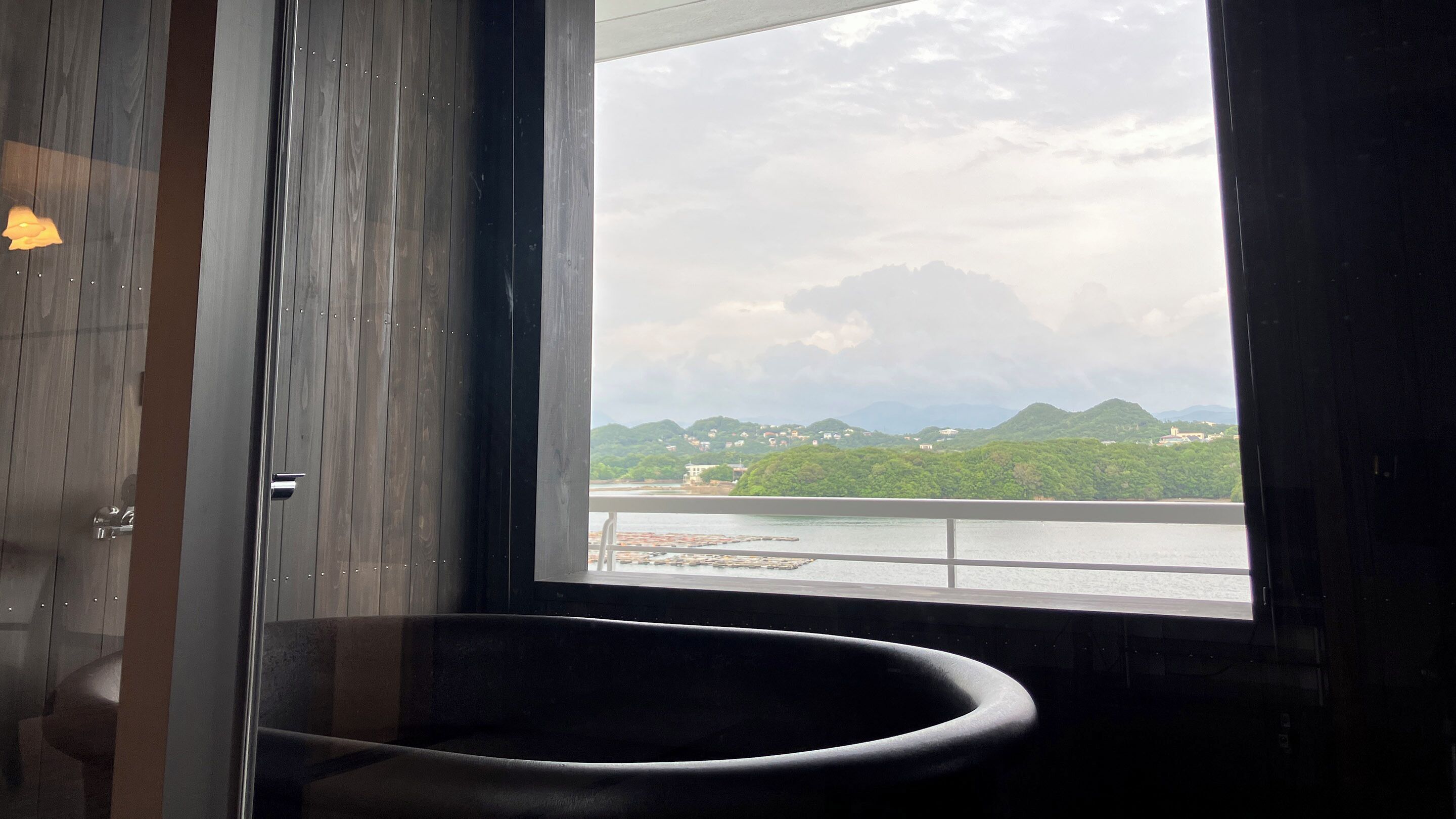 A bathroom with a large window, a bathtub, and a wooden door.