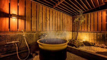 Zona de baño termal con paredes de madera y una balsa de piedra.