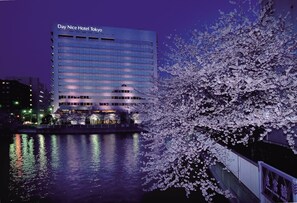 A hotel building with a sign reading "Day Nice Hotel Tokyo" at night, reflecting on a body of water, with cherry blossoms in full bloom. - Day Nice Hotel Tokyo (Tokyo)