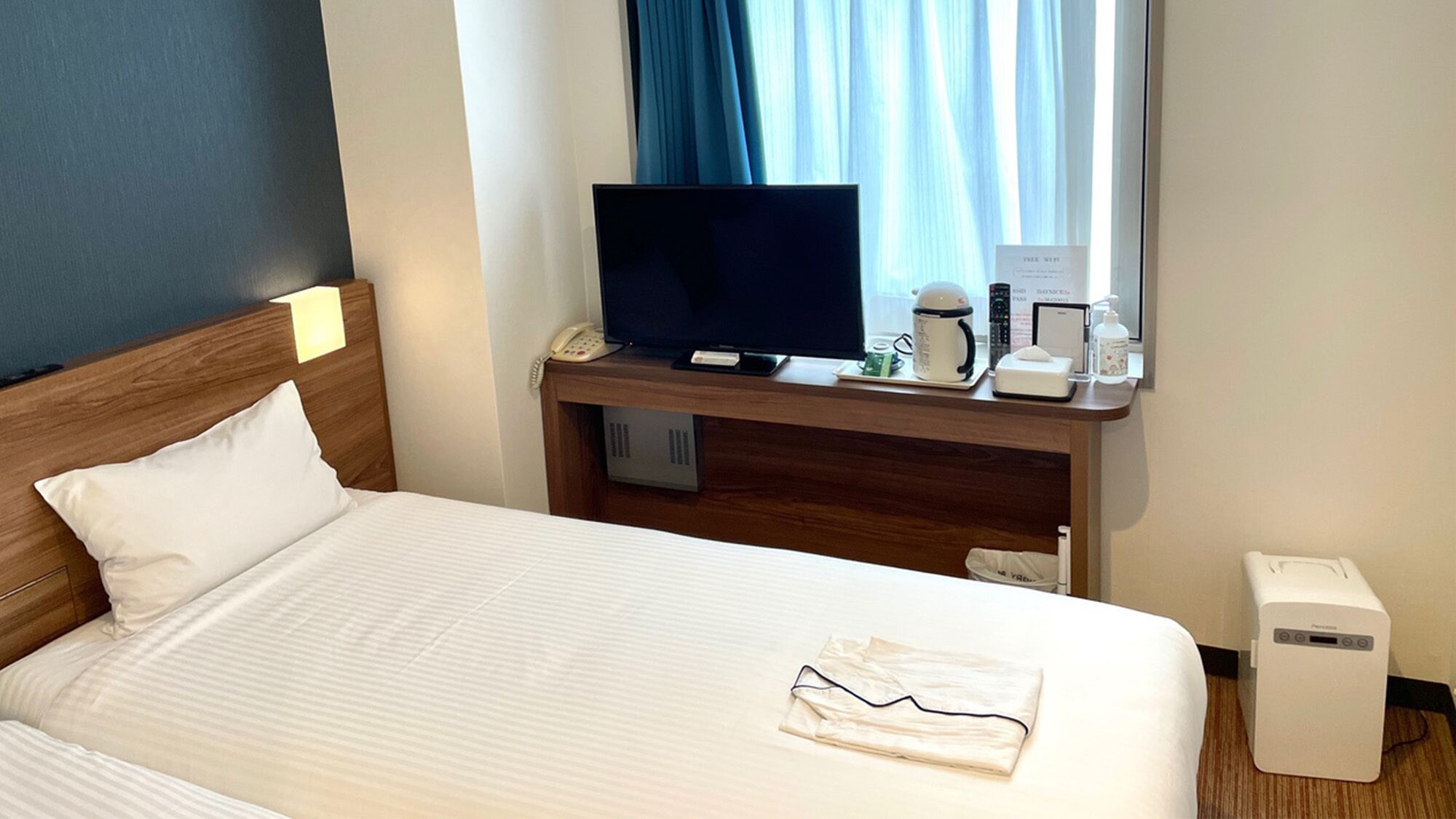 Ein Hotelzimmer mit einem Bett, einem Fernseher, einer Kaffeemaschine und einem Mülleimer.