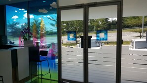 A hotel reception area with a view of a parking lot and a building with a blue and white logo. - 9 Square Hotel - Sri Kembangan (Seri Kembangan)