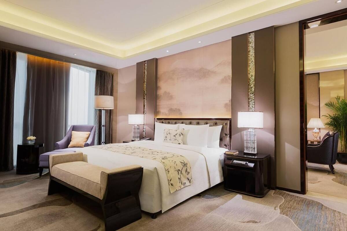 A modern hotel room with a large bed, a seating area, and a large mirror.