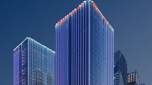 Un immeuble moderne de grande hauteur, doté d’un système d’éclairage vertical original et d’une façade en verre réfléchissant.