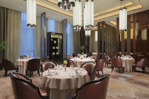 A spacious dining area with round tables, elegant chairs, and modern chandeliers. - Wanda Realm Jinhua (Jinhua)