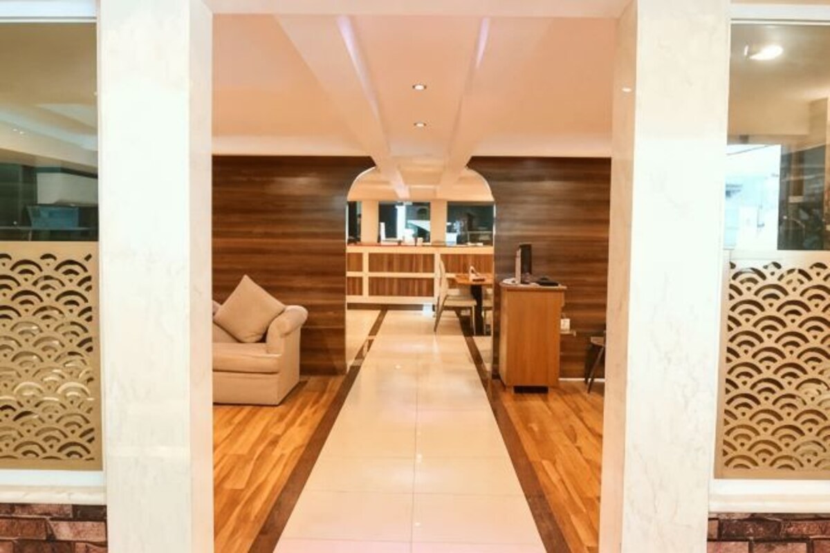 Un pasillo con un sofá, un aparador de madera y una pared con diseño.
