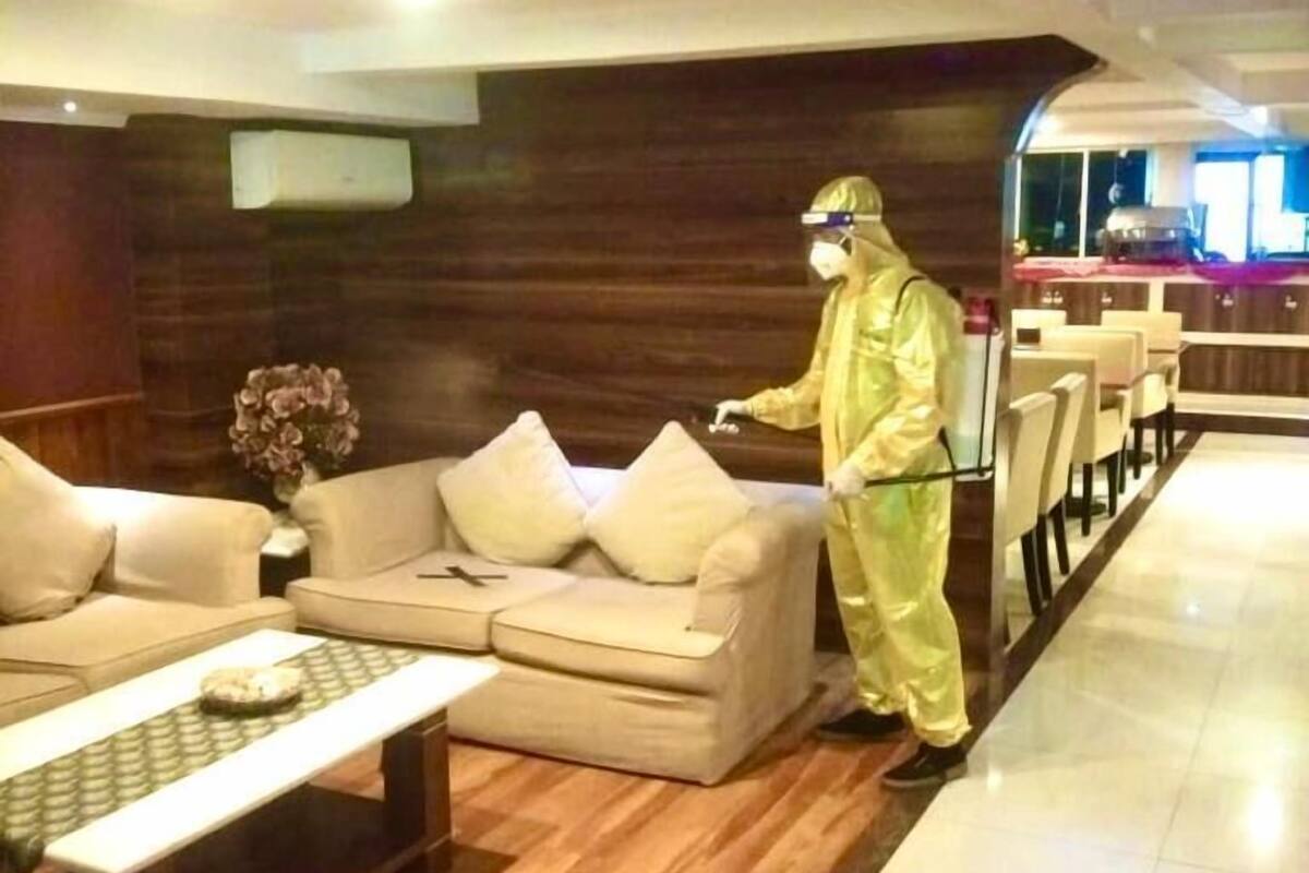 Un vestíbulo de hotel con piso de madera, un sofá, una mesa de centro y una persona con traje de protección.