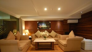 A modern living room with two sofas, a coffee table, and a painting on the wall. - Grand Kasira (Jakarta)