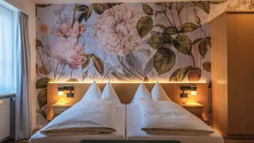 A hotel room with a large bed, two bedside tables, and a floral wallpaper.