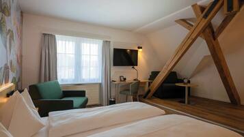 Una habitación de hotel con una cama, un escritorio con una silla, un televisor y una escalera.