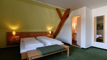 Ein Hotelzimmer mit Bett, Nachttischen, einer Bank und einem Bild an der Wand.