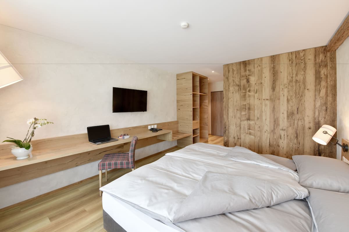 Een moderne slaapkamer met een bed, een bureau, een stoel, een televisie en inbouwkasten.