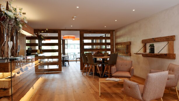 A spacious living area with wooden flooring, a dining table, and several chairs.