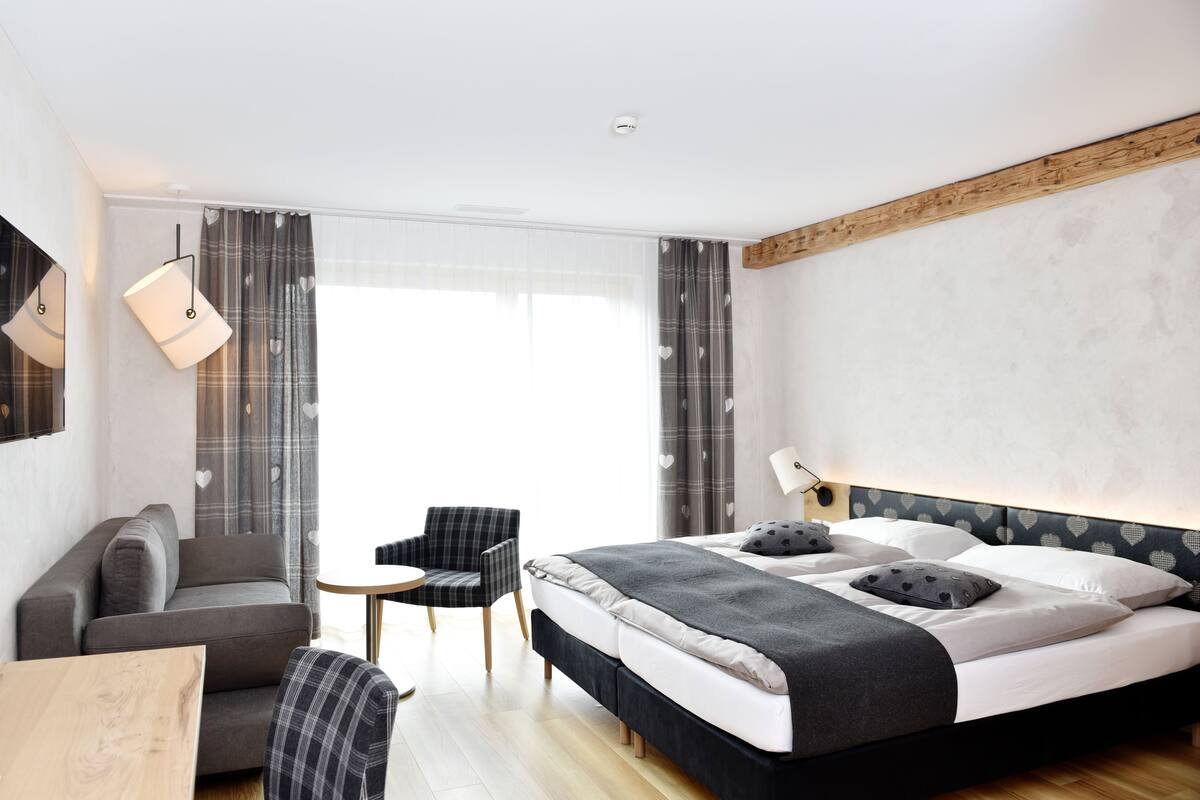 Een moderne hotelkamer met een bed, een sofa, een kleine tafel en een stoel.