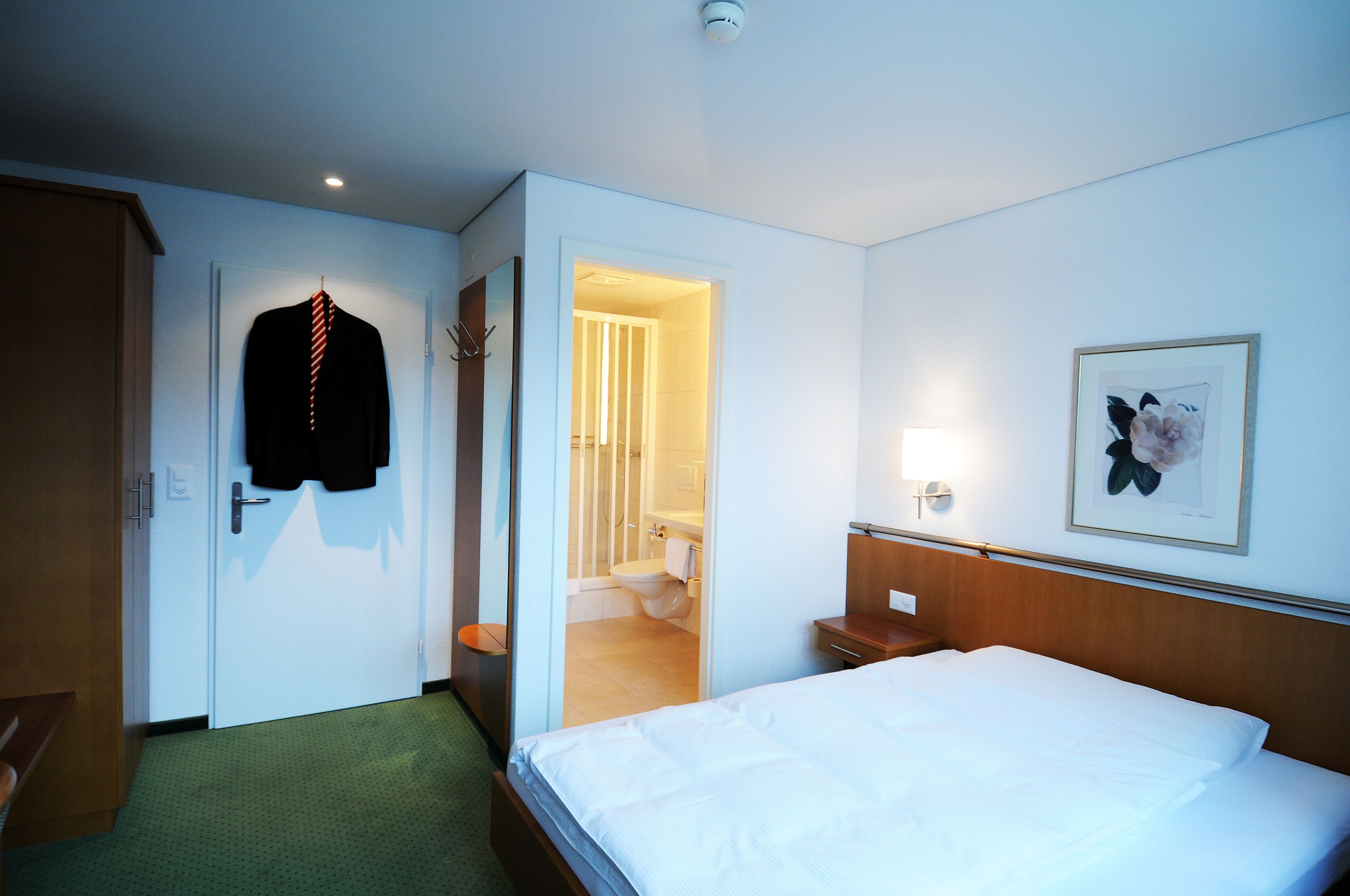 Ein Hotelzimmer mit Bett, Schrank, Badezimmer und einer Tür zu einem weiteren Raum.