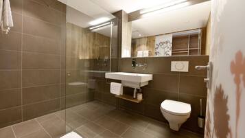 A modern bathroom with a glass shower enclosure, a white sink, and a toilet.