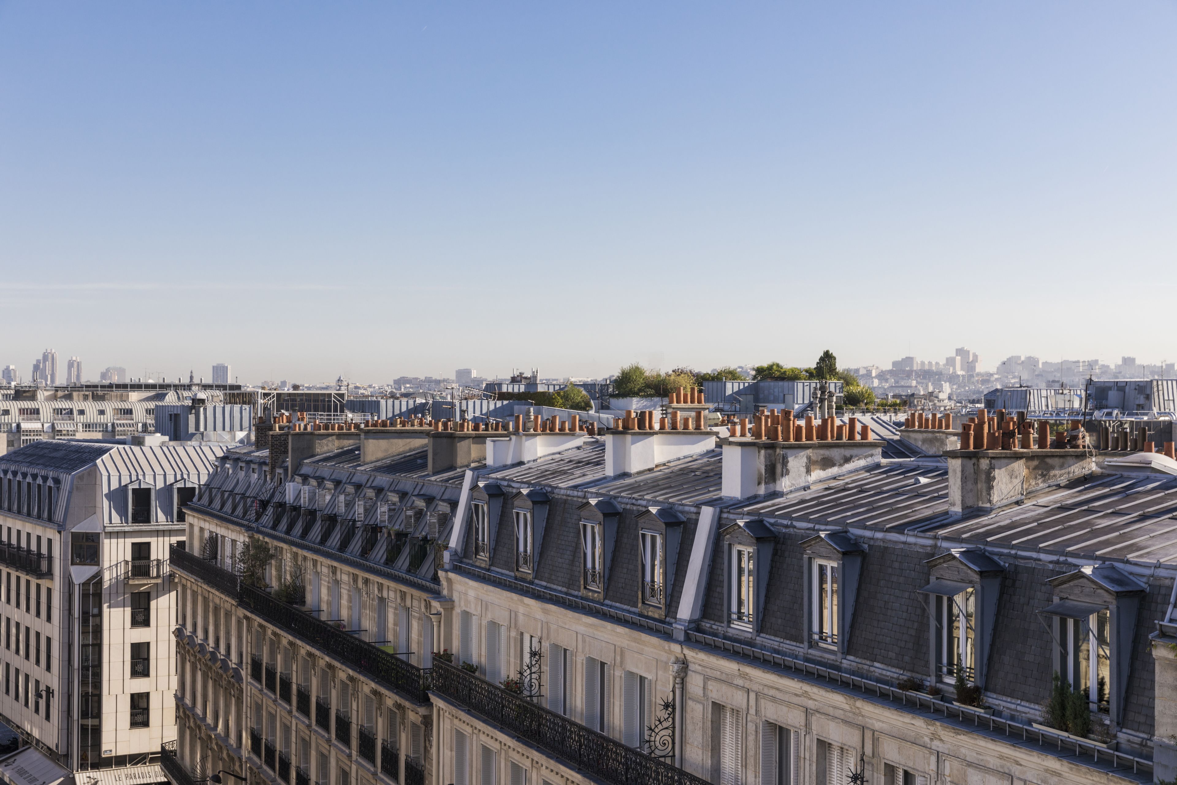 A row of residential buildings with steeply pitched roofs and dormer windows, typical of urban European architecture.