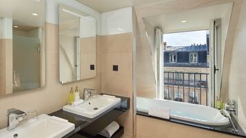 Un baño moderno con dos lavamanos, un espejo grande y una bañera.