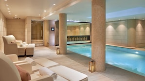 A modern spa area with a pool, lounge chairs, and a massage room.