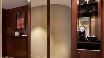 A modern hotel lobby with a wooden reception desk, a framed artwork, and a coffee machine.