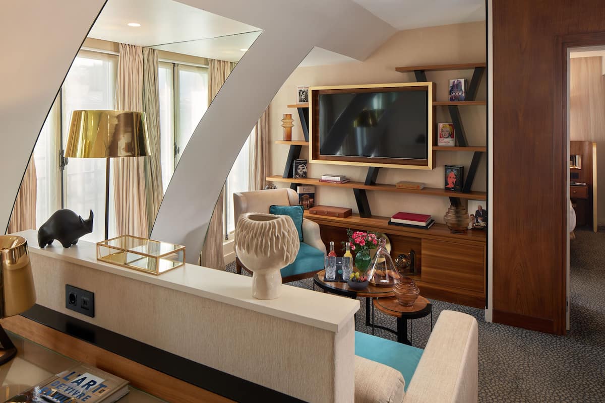 A modern living room with a flat-screen TV, a sofa, a coffee table, and a bookshelf.