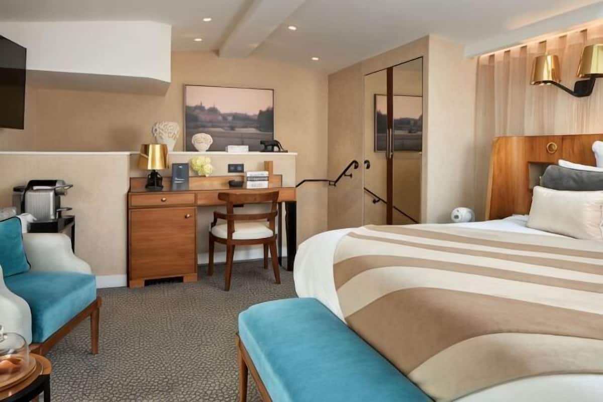 A hotel room with a bed, a desk, a chair, a sofa, and a TV.