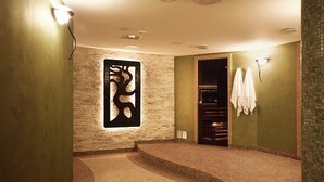 Een moderne badkamer met een stenen muur, een groot abstract kunstwerk en een handdoekhouder.