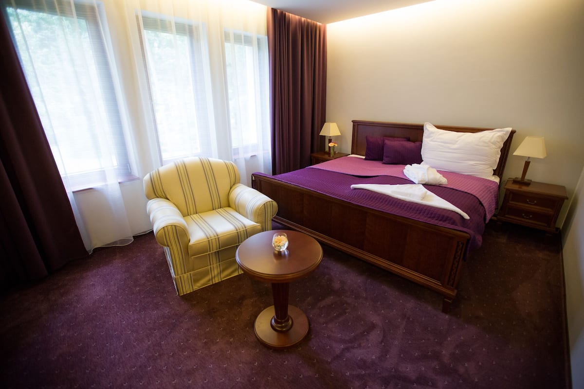 Een hotelkamer met een bed, een stoel, een klein tafeltje en een nachtkastje.