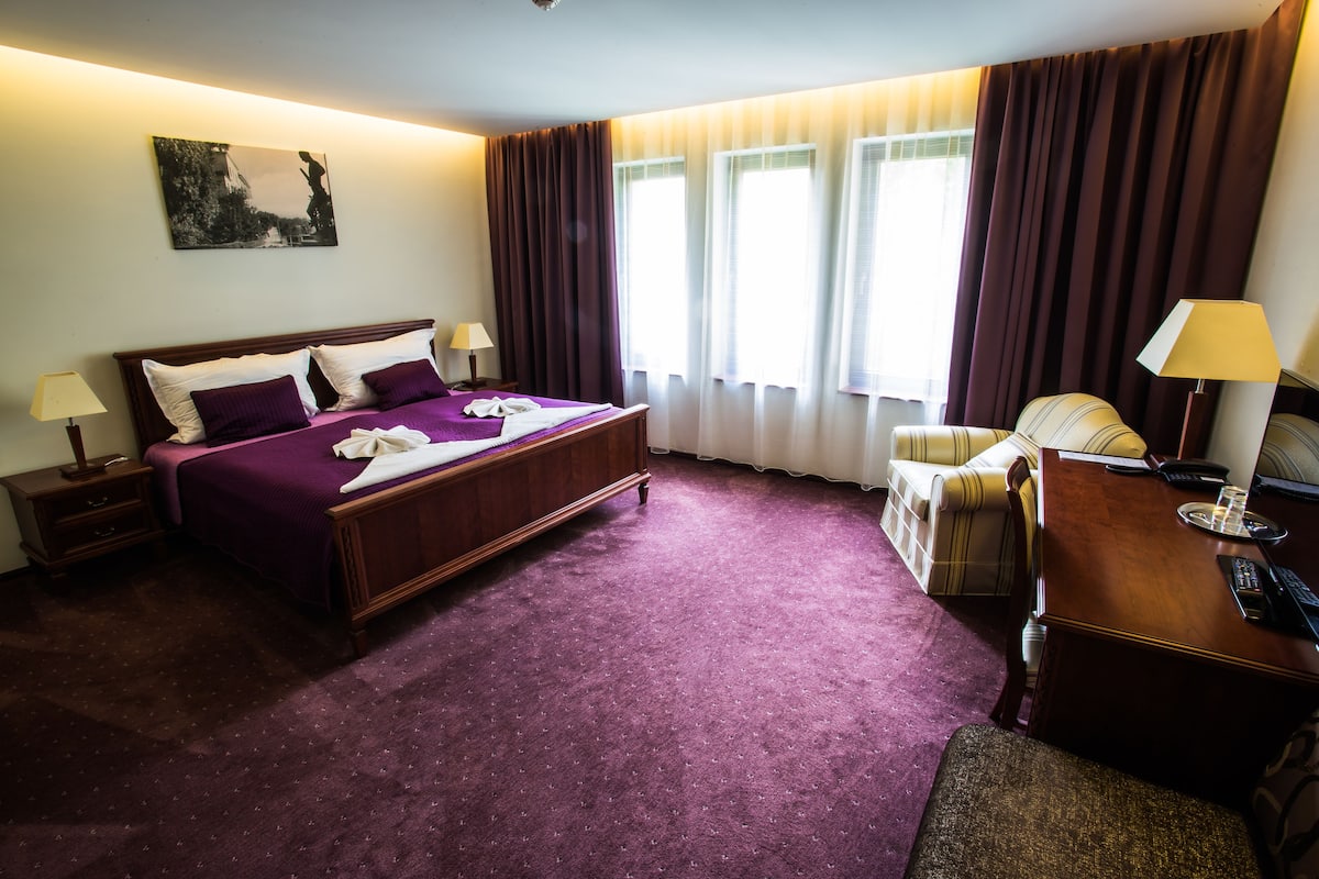 Een hotelkamer met een groot bed, een bureau en een stoel.