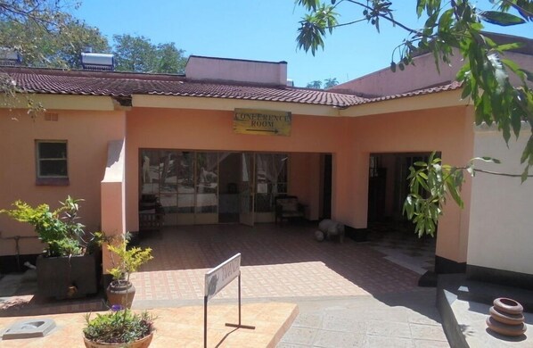 A building with a sign reading "Conference Room" and a tiled entrance area with potted plants.