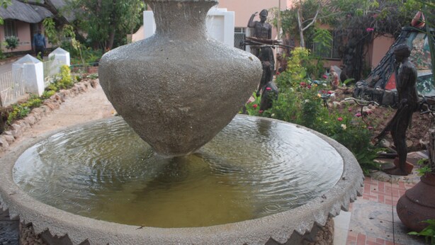 Ein großer Steinfountain mit Wasser in einer Gartenanlage.