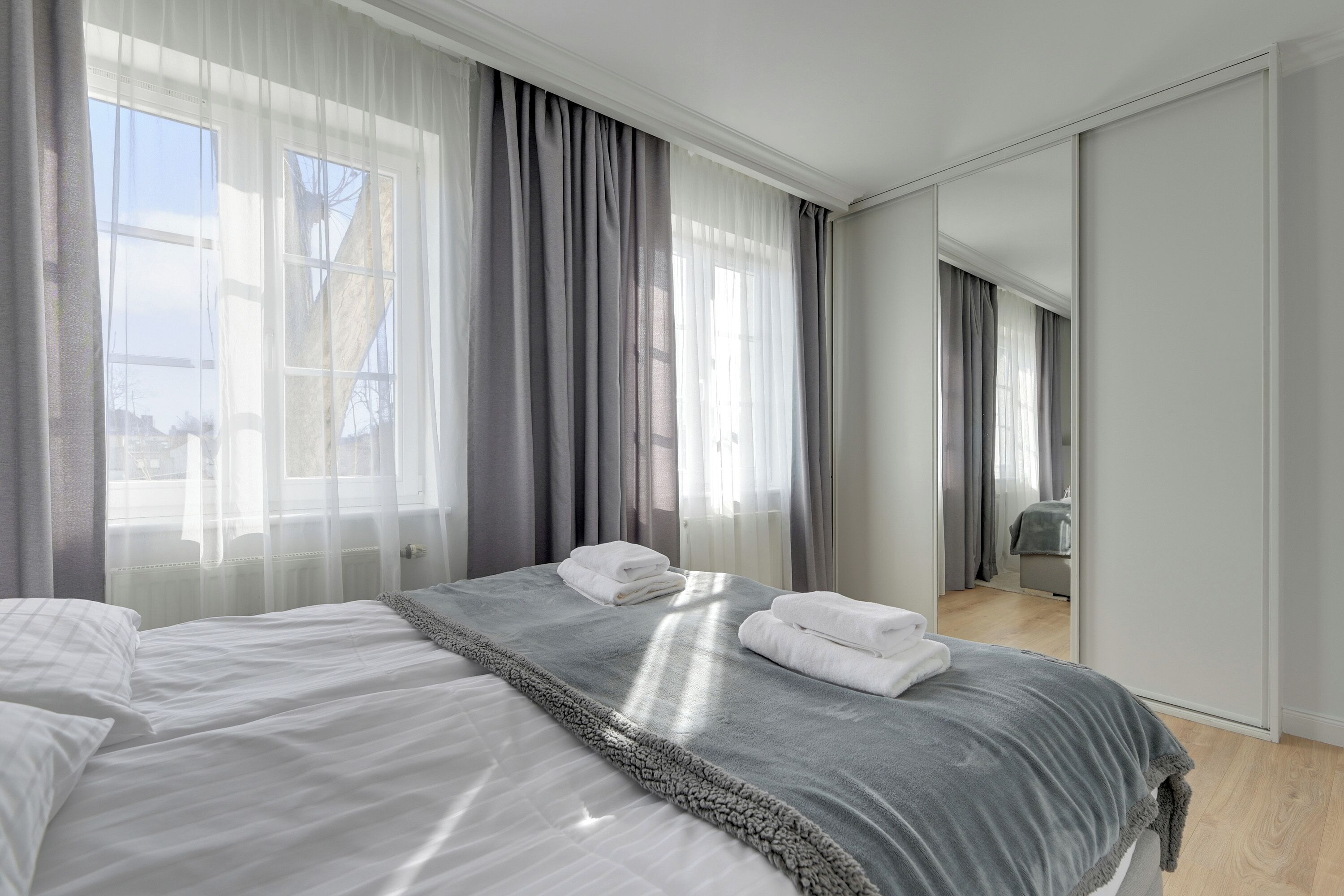 Een hotelkamer met een groot bed, een kledingkast en uitzicht door het raam.