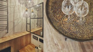 Une salle de bain moderne avec un meuble-lavabo en bois, un grand miroir et des luminaires suspendus aux formes géométriques.