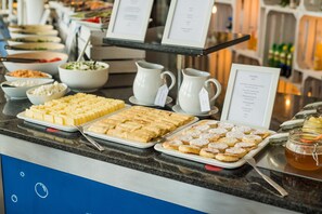 Un bufé con diversas opciones de comida, incluyendo pasteles, ensaladas y bebidas.