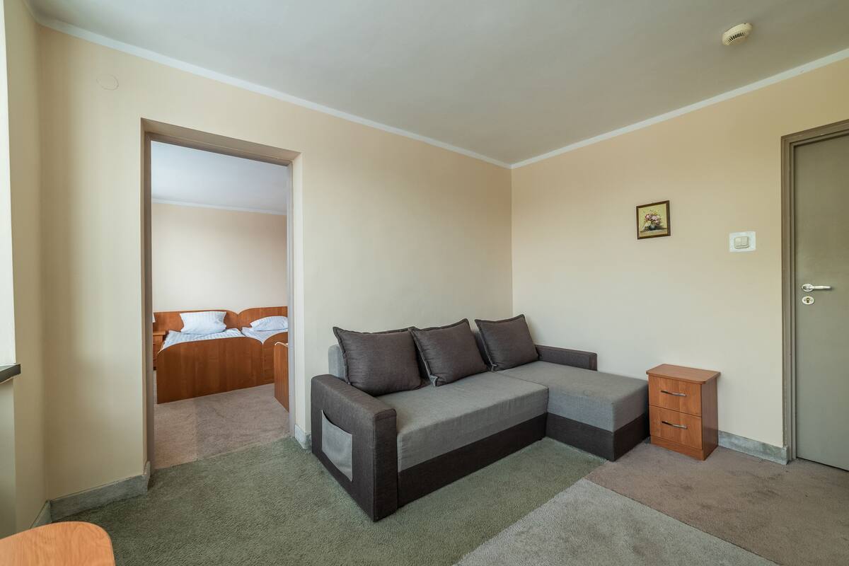A room with a sofa, a small wooden cabinet, and a door.