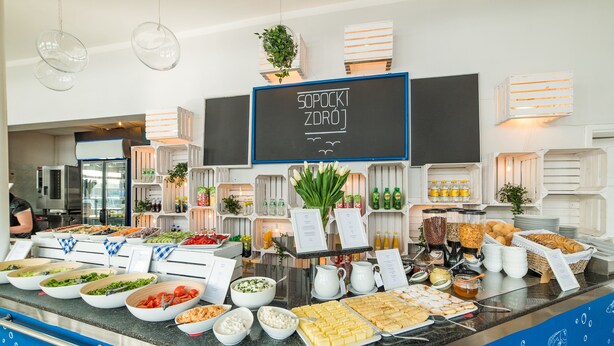 A buffet with various food items, a chalkboard menu, and a blue decorative border. - Sopocki Zdroj (Sopot)