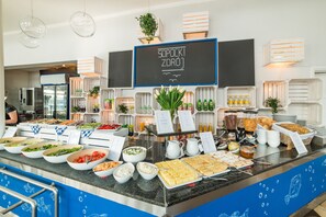 Un bufé con diferentes opciones de comida, un menú en una pizarra y un borde decorativo azul.