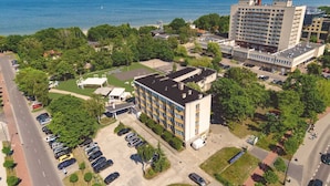 An aerial view of a residential area with a multi-story building, a parking lot, and a body of water in the background. - Sopocki Zdroj (Sopot)
