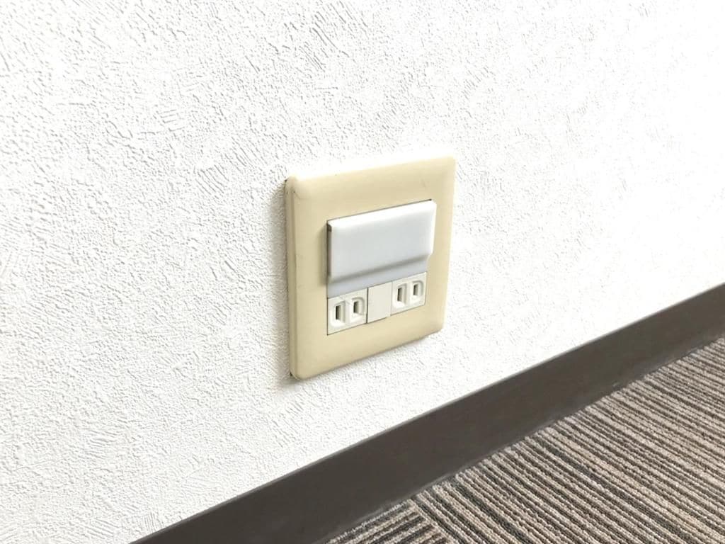 A wall-mounted electrical outlet with a switch and three sockets.